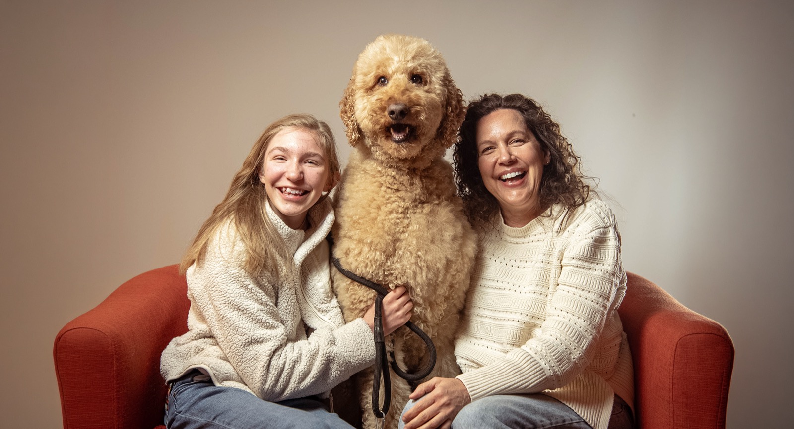 A family and their dog together on a couch, laughing